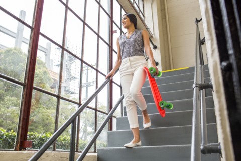 Asian woman carrying skateboard on staircase