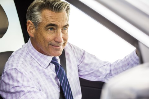 Smiling Caucasian businessman driving car
