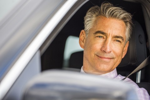 Smiling Caucasian businessman driving car