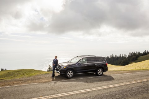 Distant Caucasian businessman leaning on car