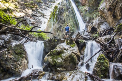 Caucasian man standing on rocks watching waterfall