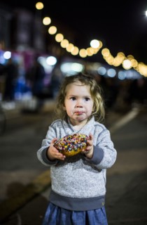 Caucasian girl eating donut outdoors at night