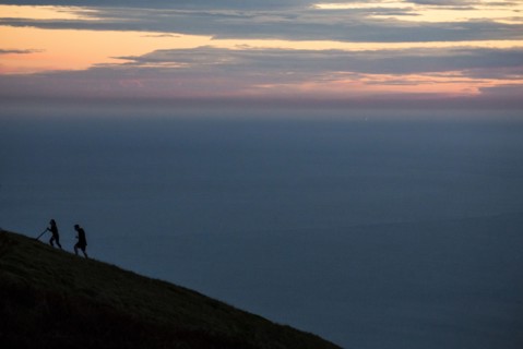 Hikers climbing hill at sunset