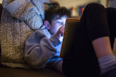 Mixed Race boy using digital tablet at night