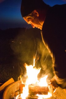 Caucasian man stoking campfire at night