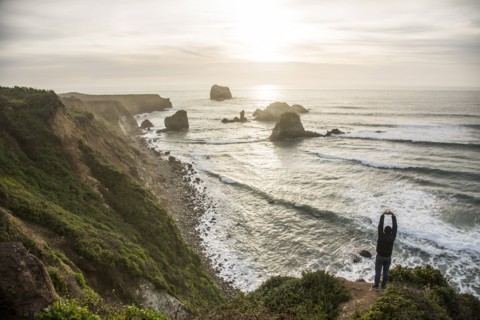 Caucasian man admiring scenic view of ocean sunset stretching arms