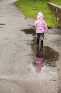 Caucasian girl wearing boots walking in puddle