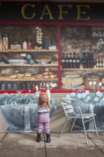 Caucasian girl standing on sidewalk admiring mural on wall