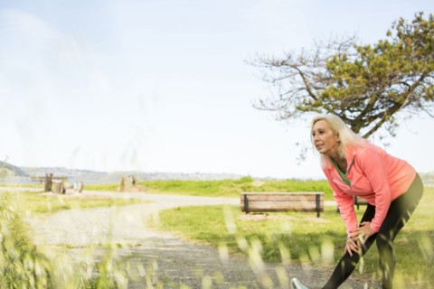Older Caucasian woman stretching leg in park