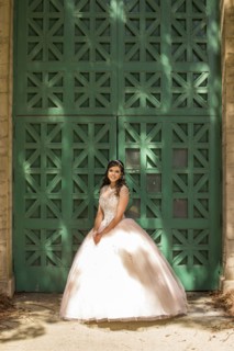 Hispanic girl wearing gown standing near green wall