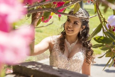 Hispanic girl wearing gown examining tree branch