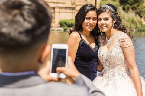 Hispanic boy photographing girls with cell phone