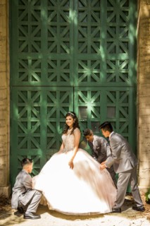 Hispanic boys wearing suits holding skirt of girl