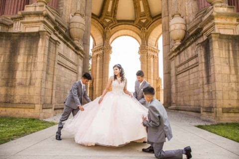 Hispanic boys holding skirt of girl