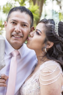 Hispanic girls wearing gown kissing father on cheek