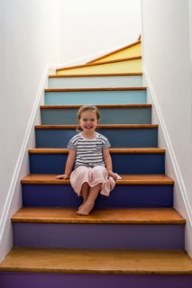 Portrait of smiling Caucasian girl sitting on multicolor staircase