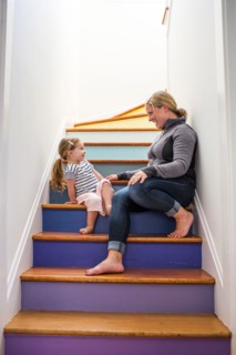 Caucasian mother and daughter laughing on multicolor staircase