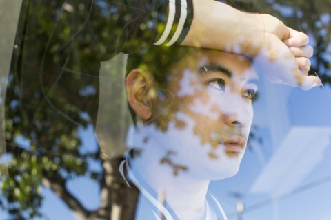 Serious Chinese man leaning on window