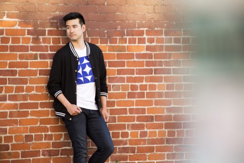 Smiling Chinese man leaning on red brick wall