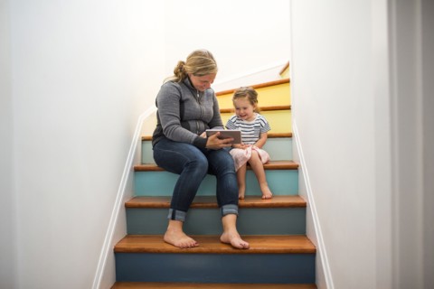 Caucasian mother and daughter using digital tablet on staircase