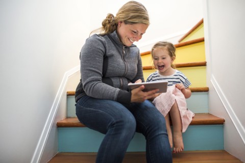 Caucasian mother and daughter using digital tablet on staircase