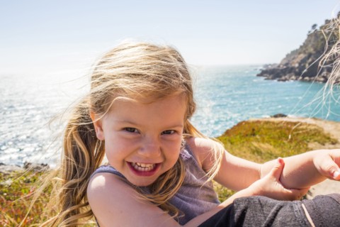 Wind blowing hair of smiling Caucasian girl near ocean
