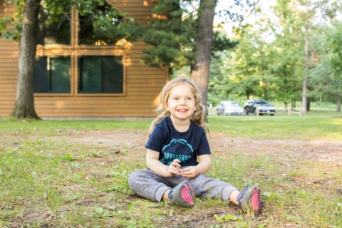 Smiling Caucasian girl sitting on ground outside house