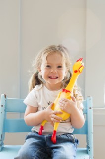 Smiling Caucasian girl holding rubber chicken