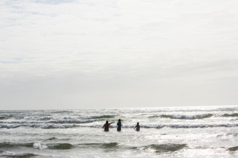 Caucasian people wading in ocean waves