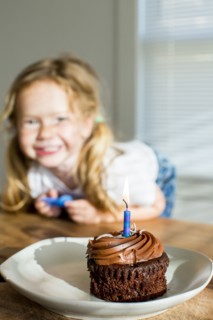 Happy Caucasian girl near birthday cupcake