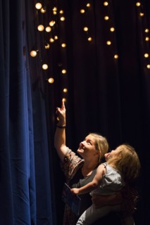 Caucasian mother and daughter looking up at blue curtain