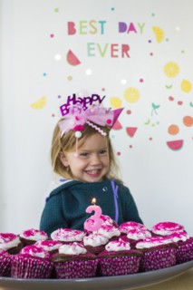 Caucasian girl holding tray of cupcakes for birthday