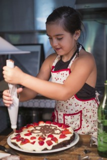 Caucasian girl decorating cake in kitchen