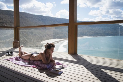 Caucasian woman sunbathing on deck over beach