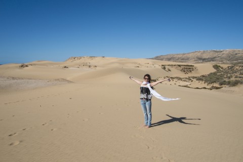 Caucasian woman cheering on sand dune
