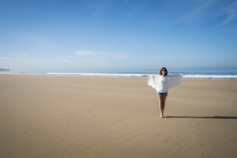 Caucasian woman walking on beach under blue sky