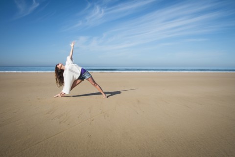 Caucasian woman practicing yoga on beach