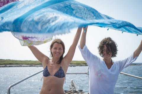 Women spreading blanket on boat in water