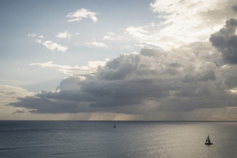 Sailboats under clouds on ocean