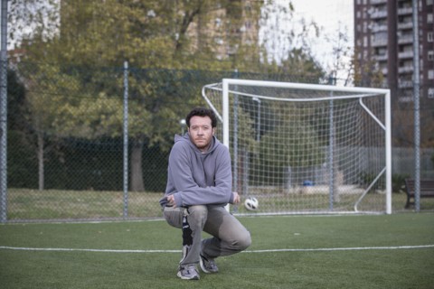 Caucasian man crouching on soccer field in urban park