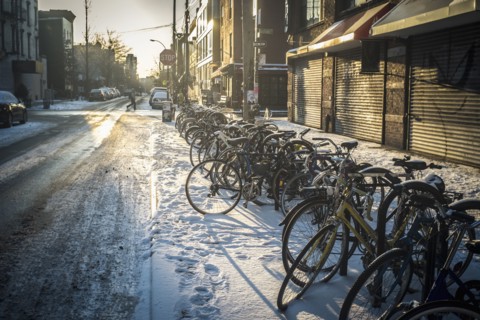Bicycles parked in snow on city sidewalk