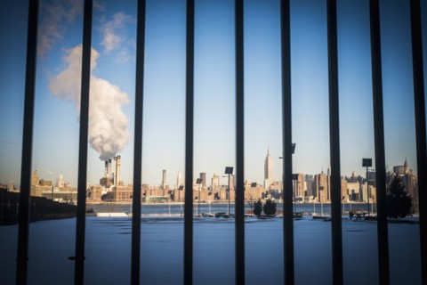 Bars in front of smokestack in city skyline