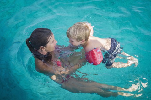 Caucasian mother teaching son to swim in pool