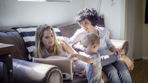 Caucasian lesbian mothers and baby son on sofa