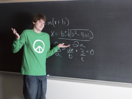 Student shrugging in confusion at chalkboard in classroom