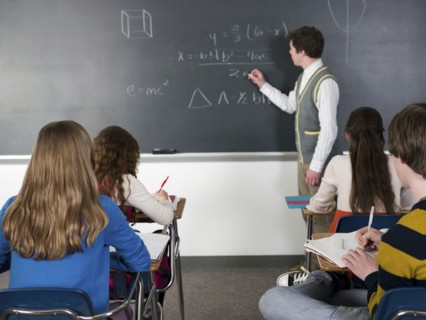 Teacher writing on chalkboard in classroom
