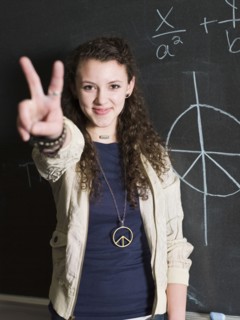 Student giving peace sign at chalkboard in classroom