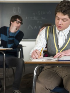 Student writing notes at desk in classroom