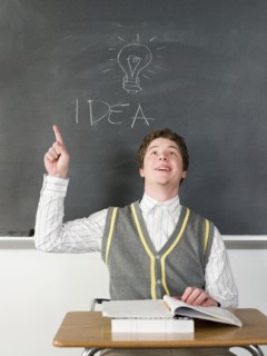 Student having idea under light bulb on chalkboard in classroom