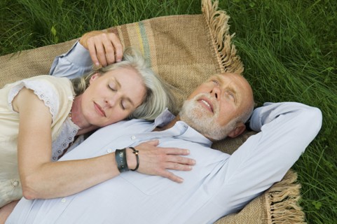 Older couple napping on picnic blanket